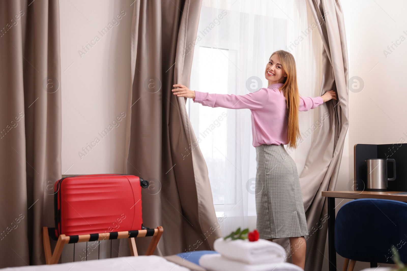 Photo of Beautiful businesswoman opening window curtains in hotel room