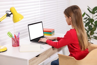 Photo of E-learning. Girl using laptop during online lesson at table indoors