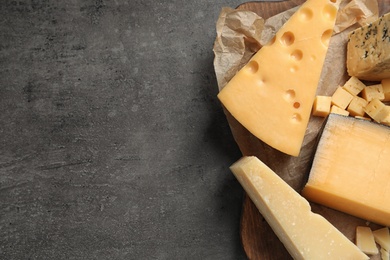 Photo of Different types of delicious cheese on grey table, top view. Space for text