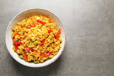 Photo of Delicious rice pilaf with vegetables on grey table, top view. Space for text
