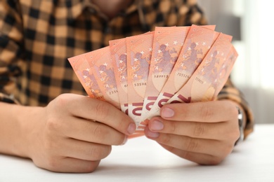Photo of Man with Euro banknotes at table indoors, closeup