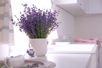 Photo of Beautiful lavender flowers on countertop in kitchen. Space for text