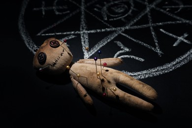 Image of Voodoo doll near ritual circle drawn on black table