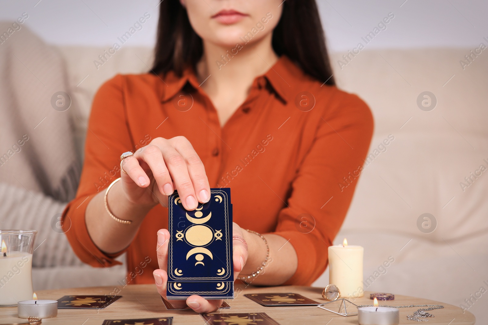 Photo of Soothsayer predicting future with tarot cards at table indoors, closeup