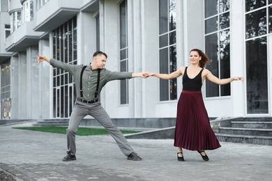 Photo of Beautiful young couple practicing dance moves on city street