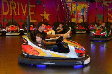 Netherlands, Groningen - May 18, 2022: Family driving electric bumper cars in amusement park