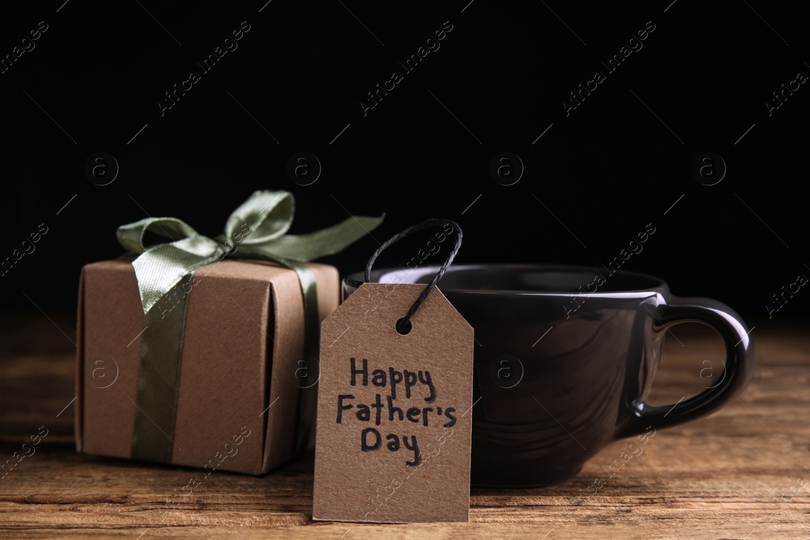 Photo of Cup of drink, gift box and tag with phrase HAPPY FATHER'S DAY on wooden table