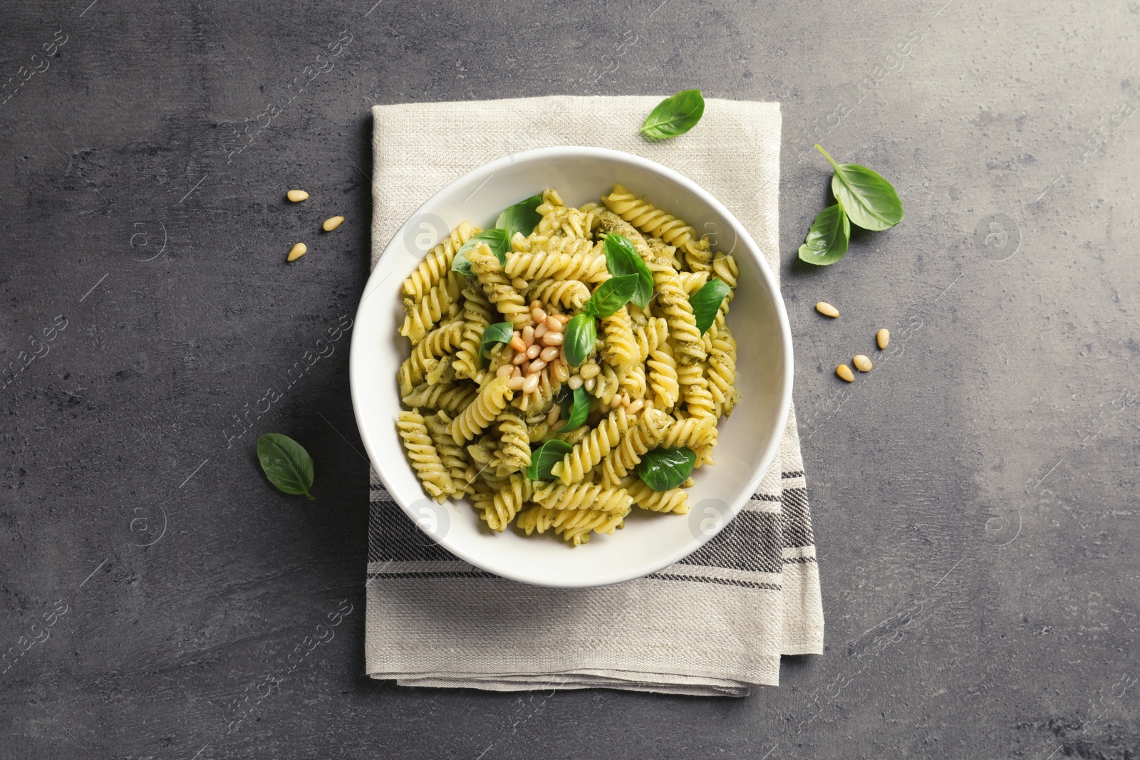 Photo of Plate of delicious basil pesto pasta on gray table, top view