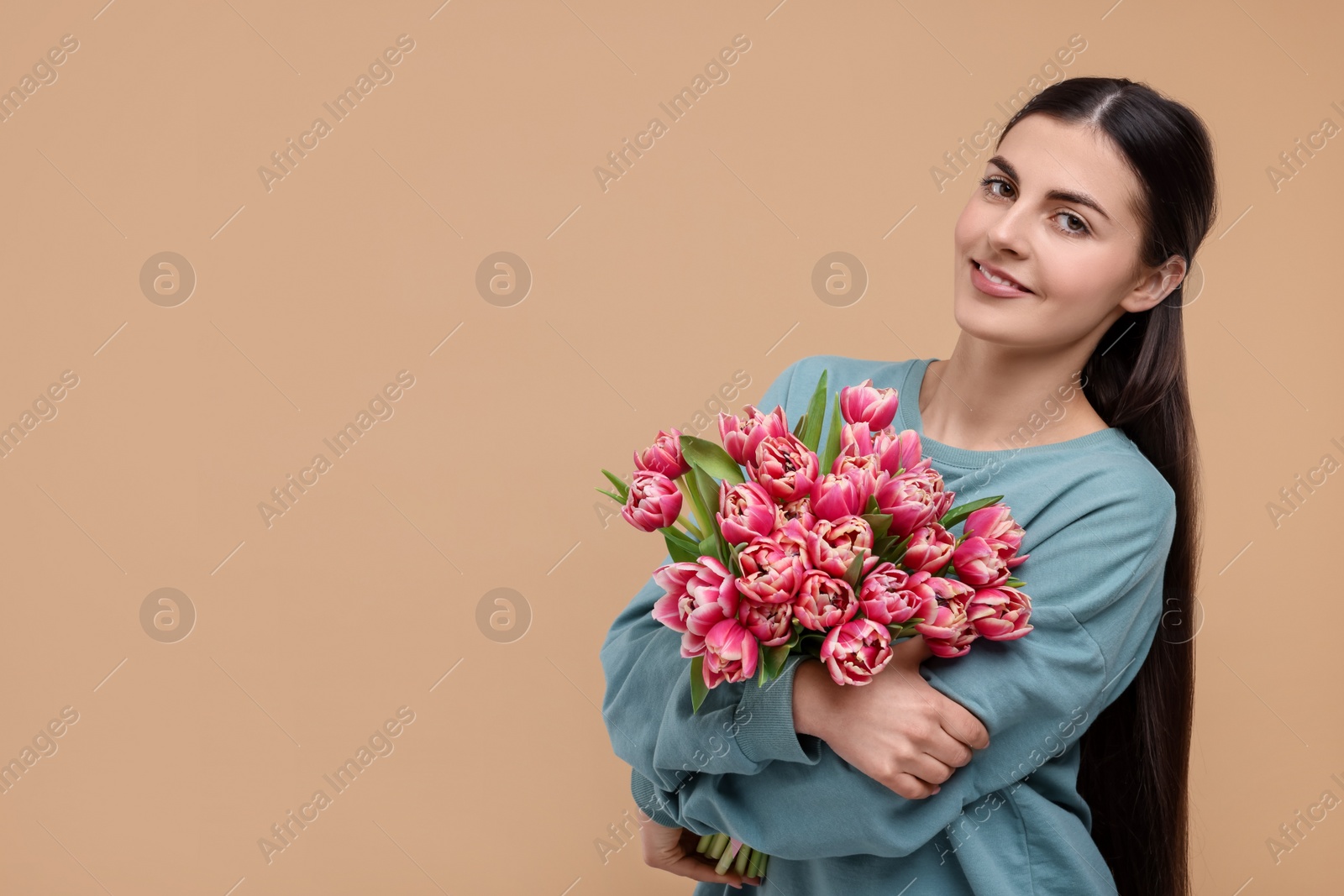 Photo of Happy young woman with beautiful bouquet on beige background. Space for text