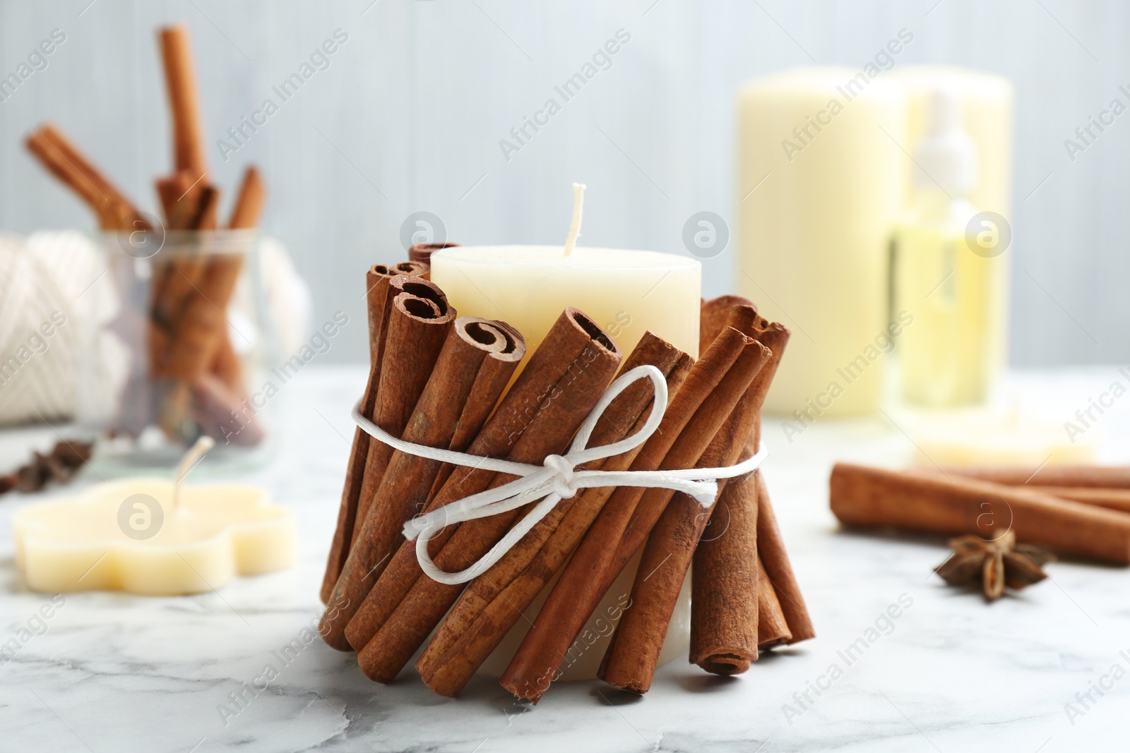 Photo of Candle with cinnamon sticks on marble table