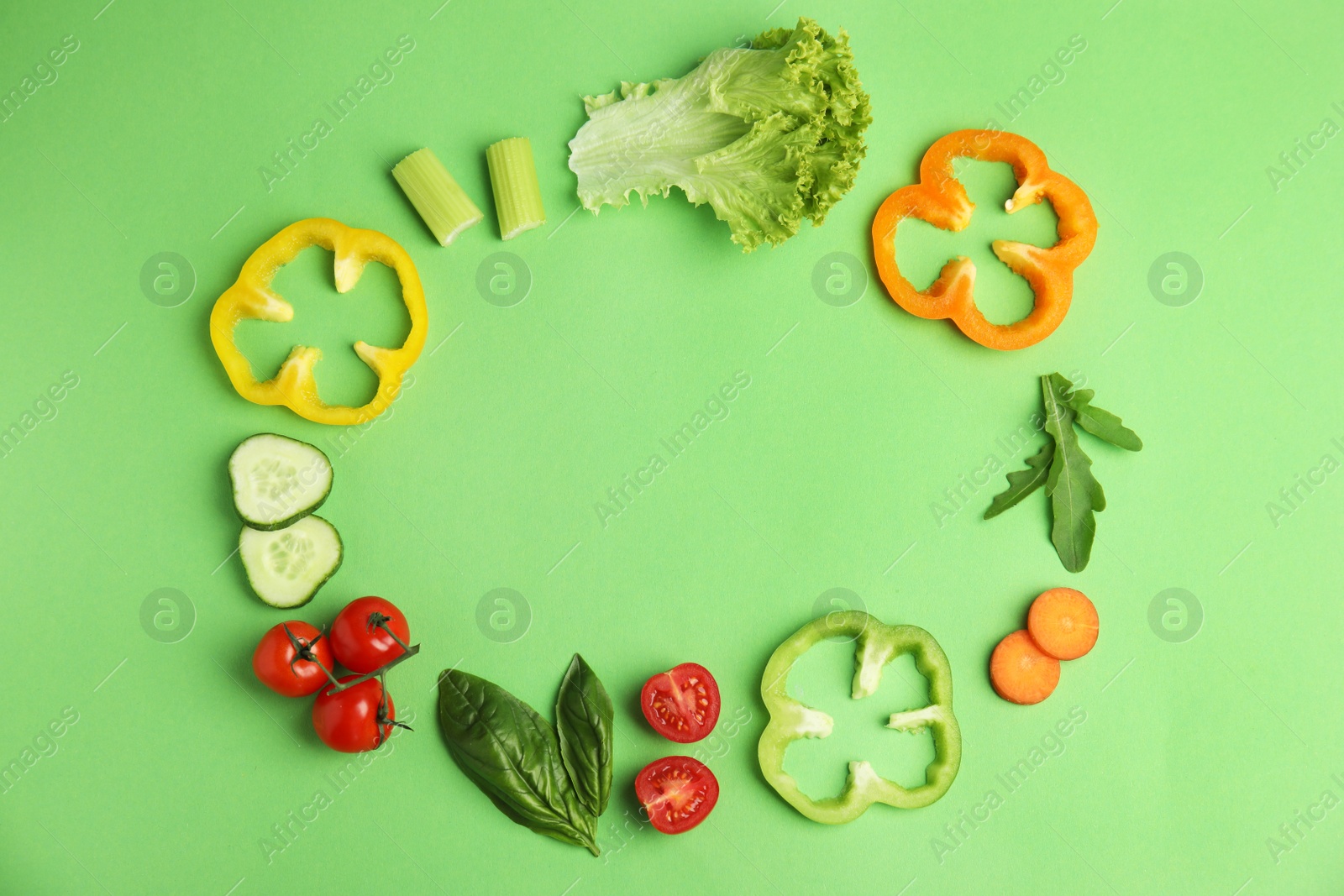 Photo of Frame made with fresh salad ingredients on green background, flat lay. Space for text