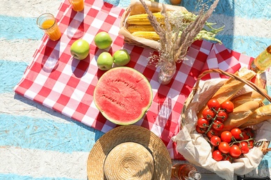 Photo of Straw hat and different products for summer picnic on checkered blanket, flat lay
