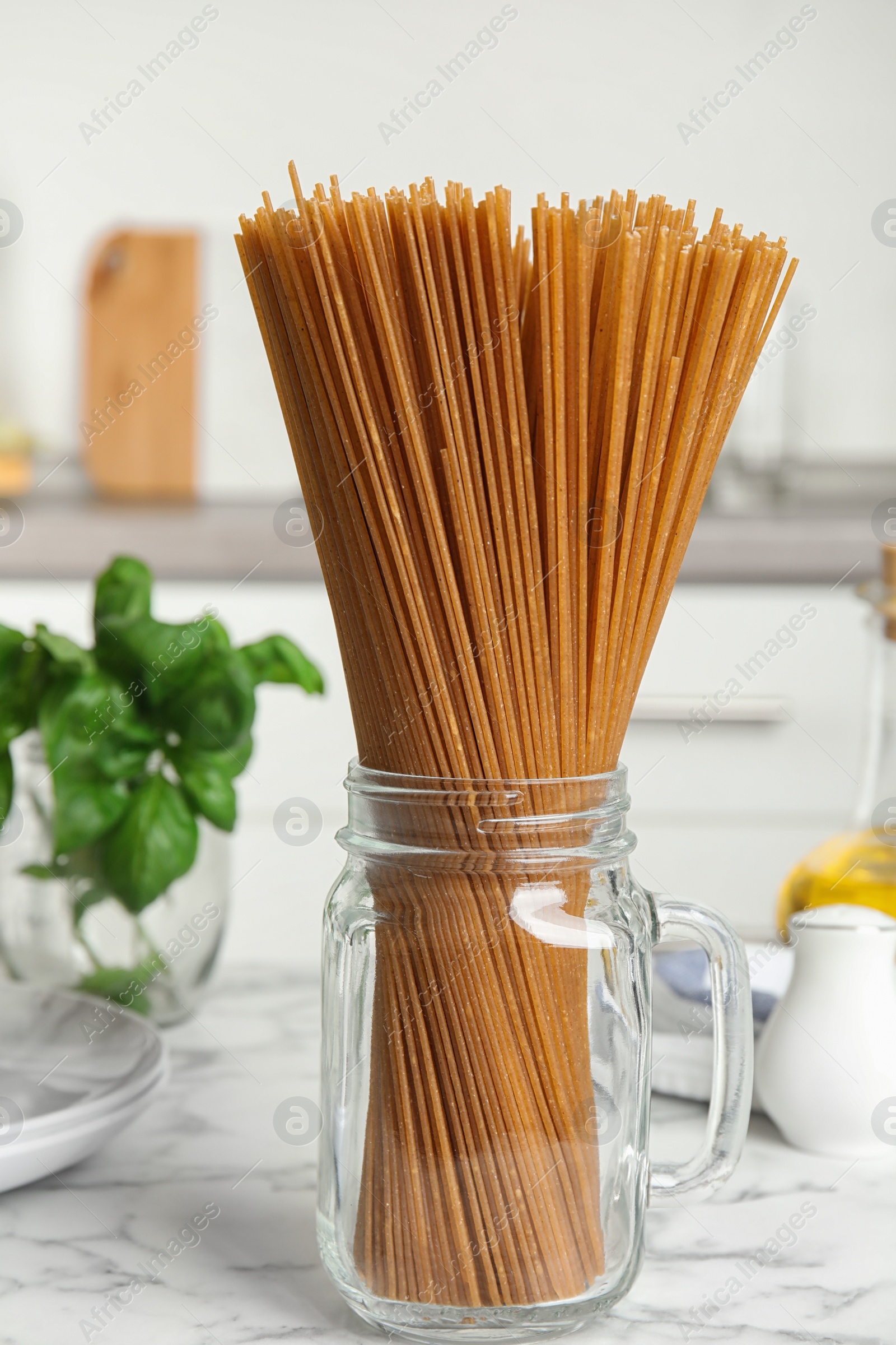 Photo of Uncooked buckwheat noodles on white marble table in kitchen