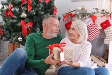 Mature couple with Christmas gift box at home