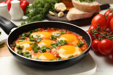 Photo of Delicious shakshuka in frying pan on white table, closeup