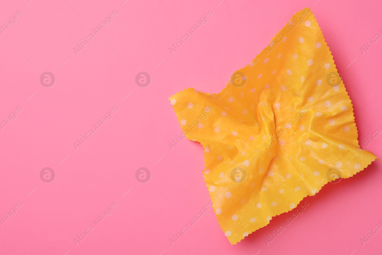 Photo of Crumpled beeswax food wrap on pink background, top view. Space for text