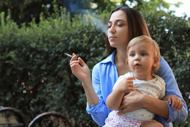 Photo of Mother with cigarette and child outdoors. Don't smoke near kids