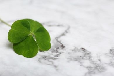 Photo of Beautiful green four leaf clover on white marble table, closeup. Space for text