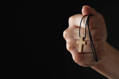 Photo of Woman holding wooden Christian cross on black background, closeup. Space for text
