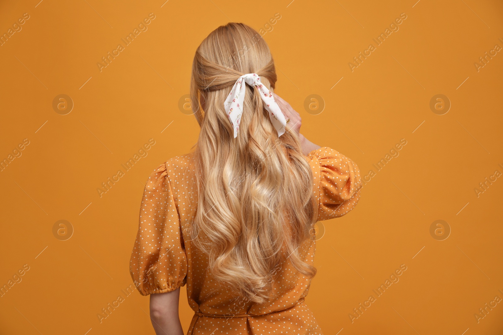 Photo of Young woman with stylish bandana on yellow background, back view