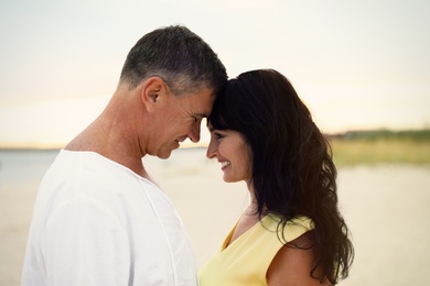 Happy mature couple spending time together on sea beach at sunset