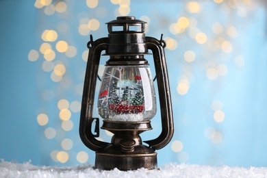Photo of Snow globe in vintage lantern against blurred Christmas lights