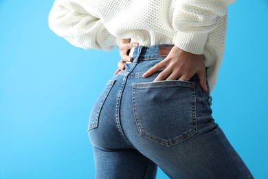 Woman wearing jeans on blue background, closeup