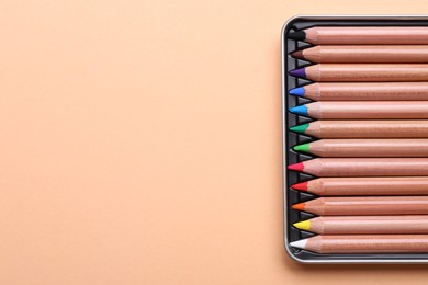 Photo of Colorful pastel pencils in box on beige background, top view with space for text. Drawing supplies