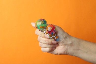 Photo of Woman squeezing colorful slime on orange background, closeup. Antistress toy