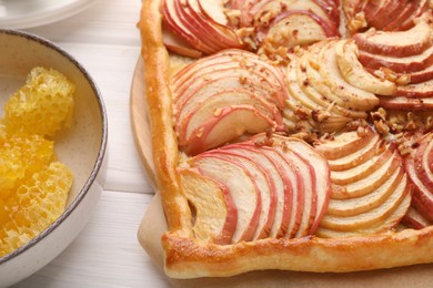 Photo of Tasty fresh apple galette and honey on white wooden table, closeup