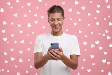 Image of Long distance love. Man chatting with sweetheart via smartphone on pink background. Hearts around him