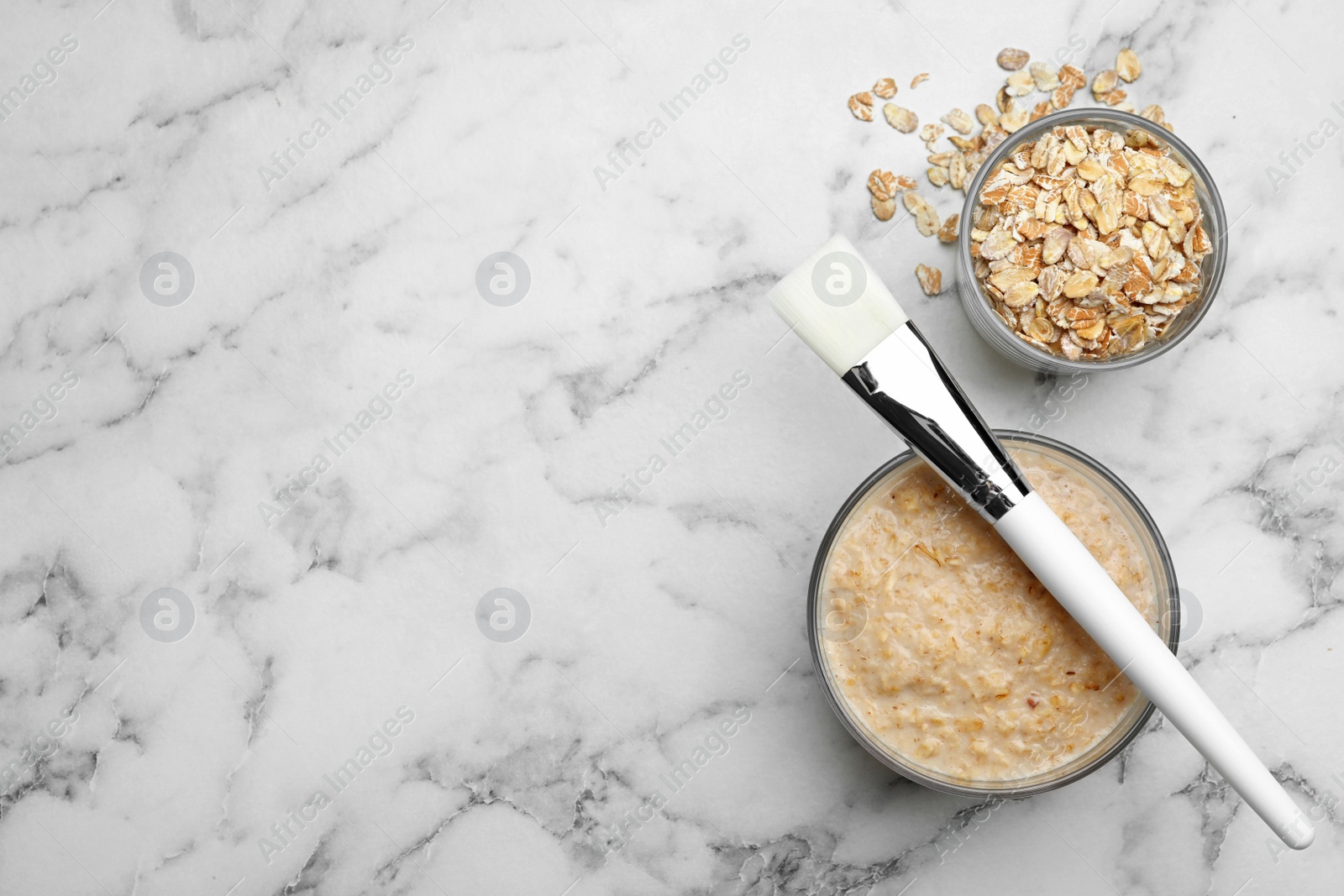 Photo of Handmade face mask made of oatmeal on white marble table, flat lay. Space for text