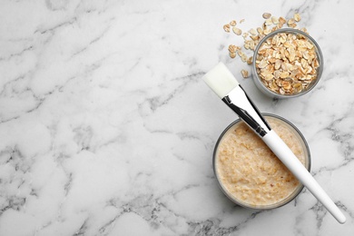 Photo of Handmade face mask made of oatmeal on white marble table, flat lay. Space for text