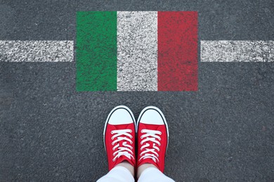 Image of Immigration. Woman standing on asphalt near flag of Italy, top view