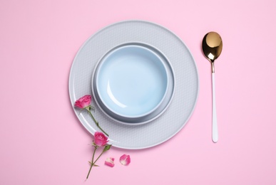 Photo of Beautiful table setting with flowers on pink background, flat lay