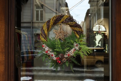 Photo of Beautiful Christmas wreath hanging on glass door