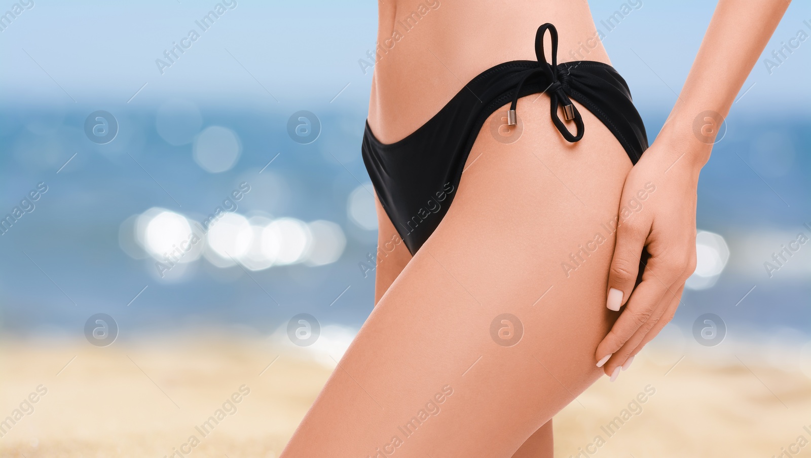 Image of Woman in stylish black bikini on sandy beach near sea, closeup. Banner with space for text