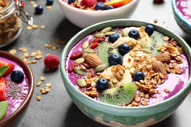 Delicious acai smoothie with toppings in bowls on table