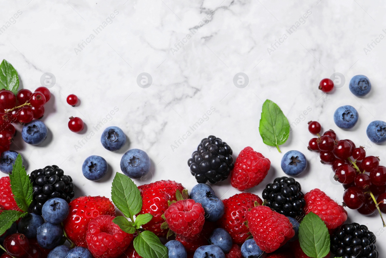 Photo of Many different fresh ripe berries on white marble table, flat lay. Space for text