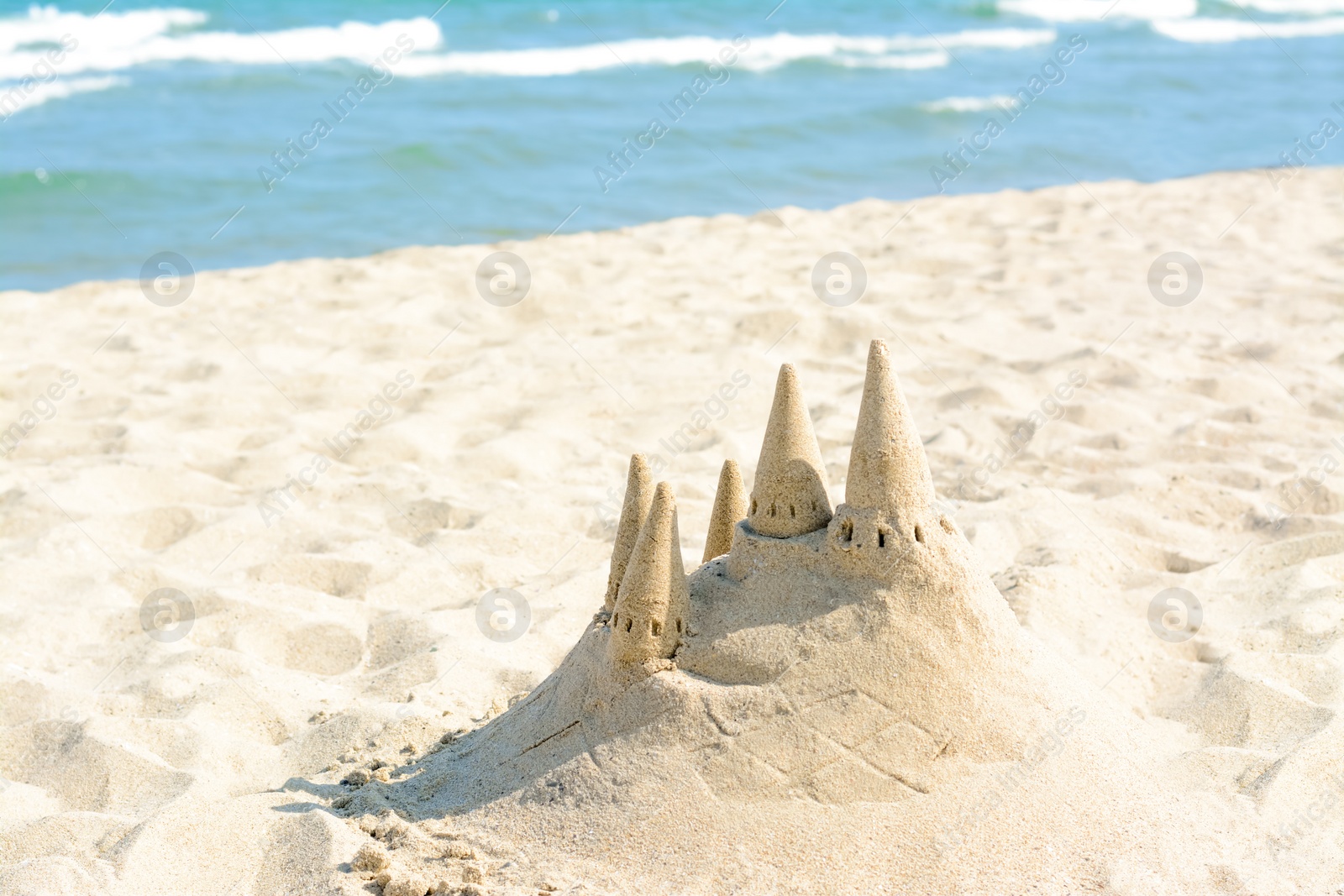 Photo of Beach with sand castle near sea on sunny day. Space for text