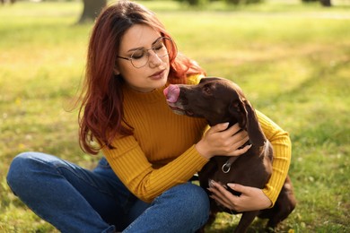 Photo of Woman with her cute German Shorthaired Pointer dog in park on spring day