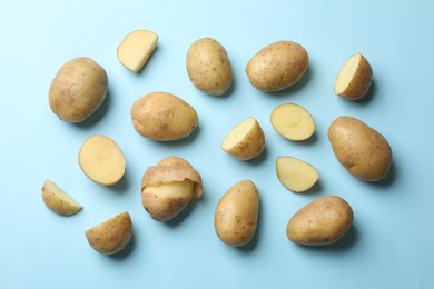 Photo of Fresh raw potatoes on light blue background, flat lay