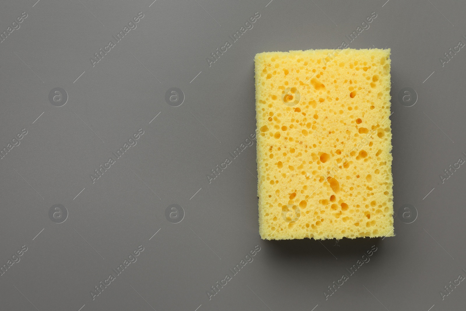 Photo of New yellow sponge on grey background, top view. Space for text