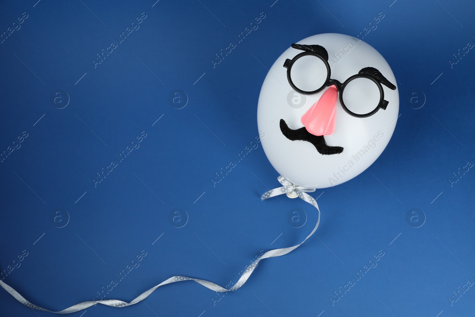 Photo of Man's face made of balloon, fake mustache, nose and glasses on blue background, top view. Space for text
