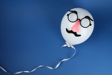 Man's face made of balloon, fake mustache, nose and glasses on blue background, top view. Space for text