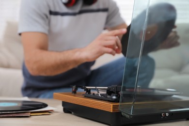 Photo of Man with vinyl record near turntable indoors, closeup
