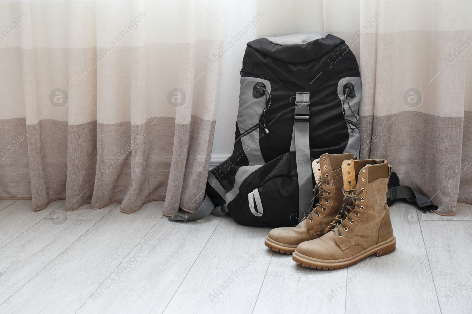 Photo of Backpack and boots on floor near window, space for text. Camping equipment