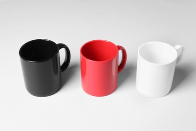 Photo of Three colorful ceramic mugs on light background
