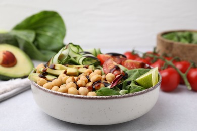 Photo of Delicious salad with chickpeas, vegetables and balsamic vinegar on white table, closeup