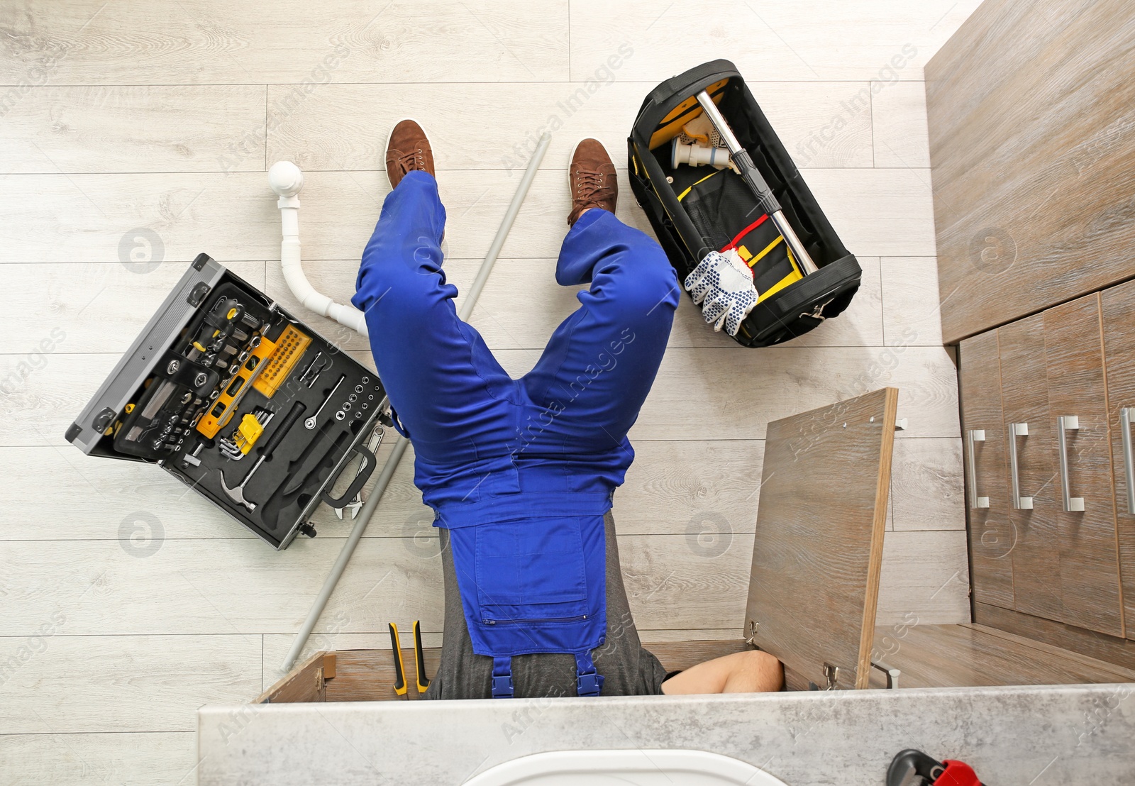 Photo of Professional plumber with set of tools working indoors, top view